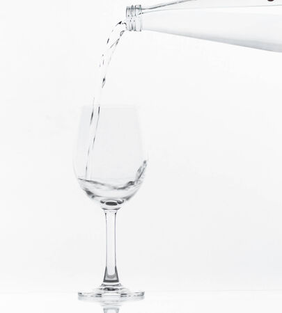 Pouring water on glass on over white backgroundの写真素材