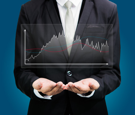 Businessman standing posture hand holding graph finance isolated on over blue backgroundの写真素材