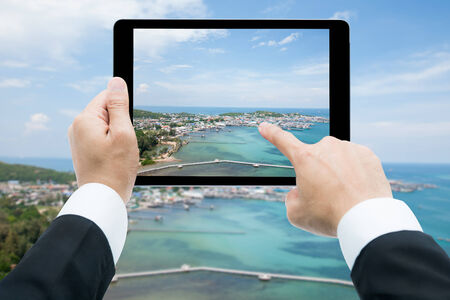 Businessman hands tablet taking pictures beach and sea on cloudの写真素材