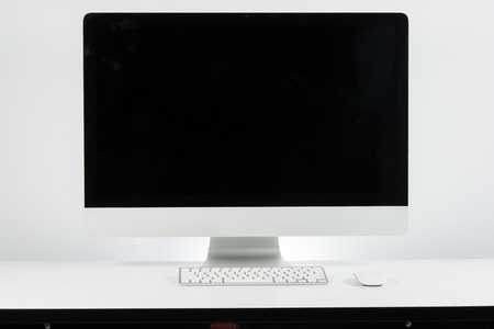 Business place of work with with computer monitor keyboard and mouse on white wallの写真素材