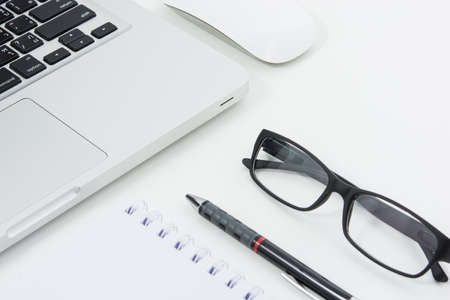 Blank business laptop, mouse, pen, glasses and note on white tableの写真素材