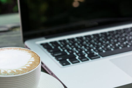 Coffee cup and laptop business on wood tableの写真素材