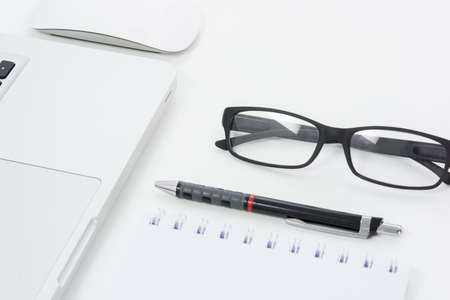 Blank business laptop, mouse, pen, glasses and note on white tableの写真素材