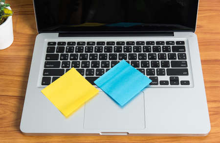 Laptop and stick note on wooden tableの写真素材