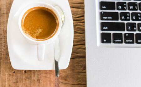 Coffee cup and laptop in coffee shop on wooden tableの写真素材