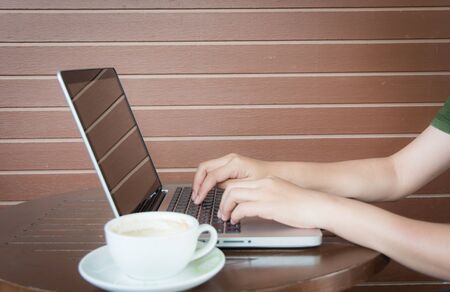 Close up woman hands working with laptop in coffee shop tableの写真素材