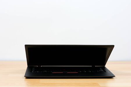 Black laptop on wooden table on white wallの写真素材