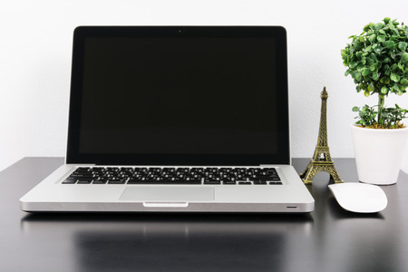 Laptop and flower pot on black wooden table on wall backgroundの写真素材
