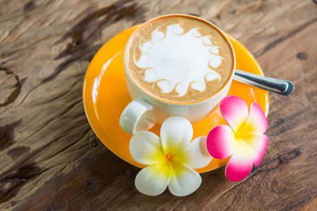 Yellow cup of coffee on wooden backgroundの写真素材