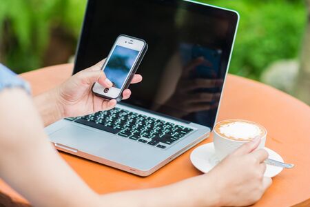 Woman hands typing on laptop outdoors in cafeの写真素材