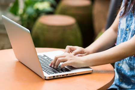 Woman hands typing on laptop outdoors in cafeの写真素材
