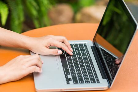 Woman hands typing on laptop outdoors in cafeの写真素材