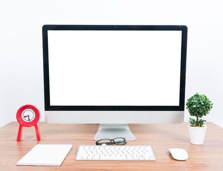 Office monitor computer, mouse on wooden table and white wall backgroundの写真素材