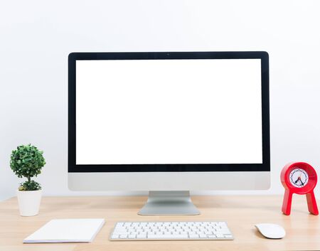 Office monitor computer, mouse on wooden table and white wall backgroundの写真素材