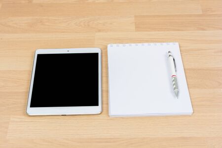 White digital Tablet on wooden table with pencil and book noteの写真素材