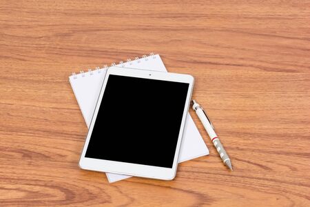 White digital Tablet on wooden table with pencil and book noteの写真素材