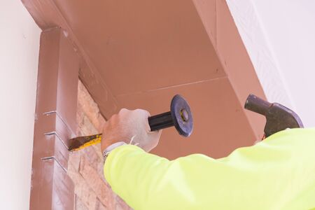 Construction worker demolishing old brick wall with chisel toolの写真素材