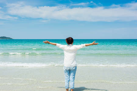 Young woman in summer standing on beach and looking to the seaの写真素材