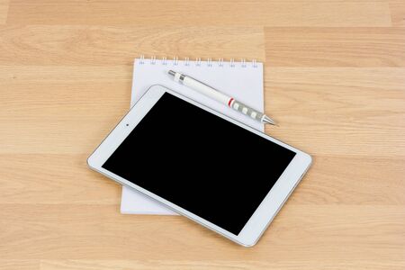 White digital Tablet on wooden table with pencil and book noteの写真素材