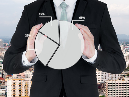 Businessman standing posture hand holding graph finance on City backgroundの写真素材