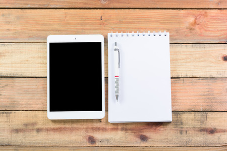 Tablet device, pen and note book on wooden workspace tableの写真素材