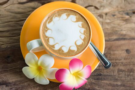 Yellow cup of coffee on wooden backgroundの写真素材