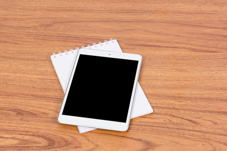 White digital Tablet on wooden table with pencil and book noteの写真素材
