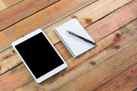 Tablet device, pen and note book on wooden workspace tableの写真素材