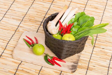 Thai Tom Yam soup herbs and spices, lemongrass, Kaffir Lime leaves, Galangal, Lemon and Chilli in basket on wooden backgroundの写真素材