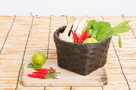 Thai Tom Yam soup herbs and spices, lemongrass, Kaffir Lime leaves, Galangal, Lemon and Chilli in basket on wooden backgroundの写真素材