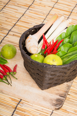 Thai Tom Yam soup herbs and spices, lemongrass, Kaffir Lime leaves, Galangal, Lemon and Chilli in basket on wooden backgroundの写真素材