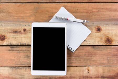 Tablet device, pen and note book on wooden workspace table