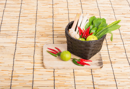 Thai Tom Yam soup herbs and spices, lemongrass, Kaffir Lime leaves, Galangal, Lemon and Chilli in basket on wooden backgroundの写真素材