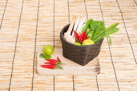 Thai Tom Yam soup herbs and spices, lemongrass, Kaffir Lime leaves, Galangal, Lemon and Chilli in basket on wooden backgroundの写真素材