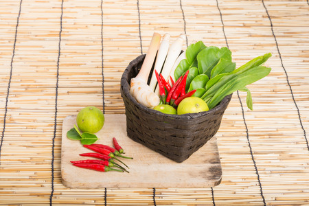 Thai Tom Yam soup herbs and spices, lemongrass, Kaffir Lime leaves, Galangal, Lemon and Chilli in basket on wooden backgroundの写真素材