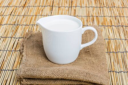 Cow milk and ceramic jug on wooden tableの写真素材