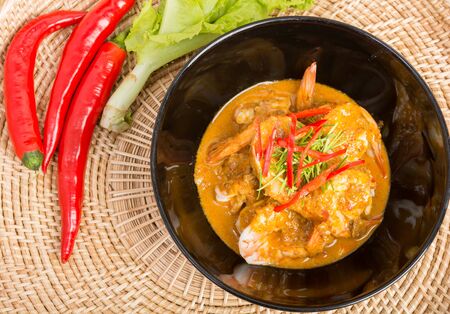 Curry fried shrimps in black cup closeup on table with wooden backgroundの写真素材