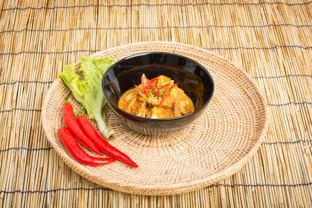 Curry fried shrimps in black cup closeup on table with wooden backgroundの写真素材