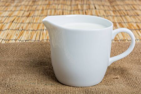 Cow milk and ceramic jug on wooden tableの写真素材