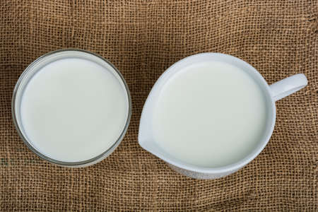 Cow milk and ceramic jug on wooden tableの写真素材