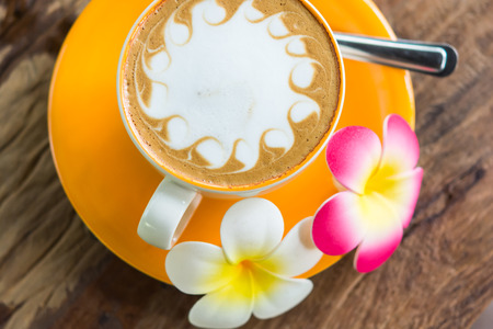 Yellow cup of coffee on wooden backgroundの写真素材