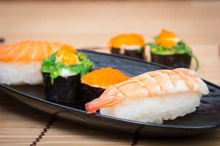 sushi in black dish on wooden backgroundの写真素材