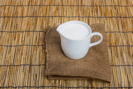 Cow milk and ceramic jug on wooden tableの写真素材