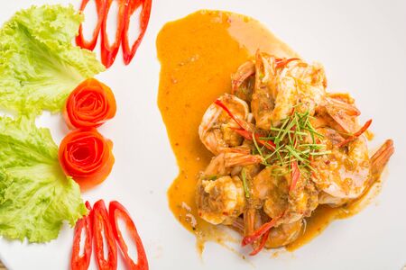 Curry fried shrimps and cooked rice in white dish closeup on table with wooden backgroundの写真素材
