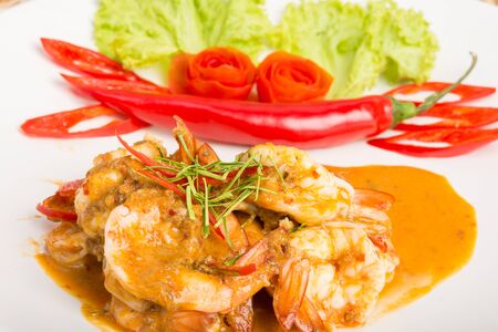 Curry fried shrimps and cooked rice in white dish closeup on table with wooden backgroundの写真素材