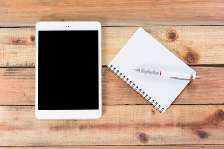 Tablet device, pen and note book on wooden workspace table