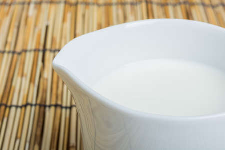 Cow milk and ceramic jug on wooden tableの写真素材