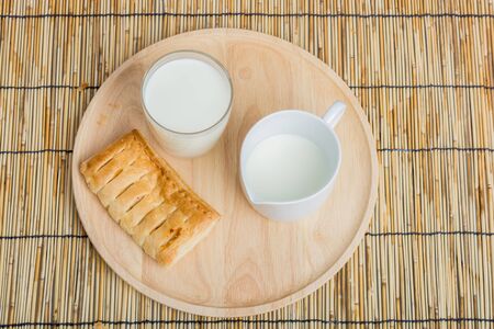 Breakfast pitcher of milk and bread on wooden tableの写真素材