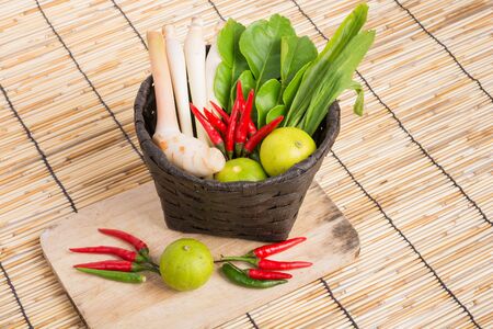 Thai Tom Yam soup herbs and spices, lemongrass, Kaffir Lime leaves, Galangal, Lemon and Chilli in basket on wooden backgroundの写真素材