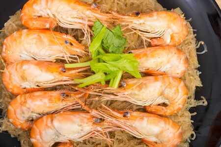 baked vermicelli with shrimp in black dish on wooden backgroundの写真素材
